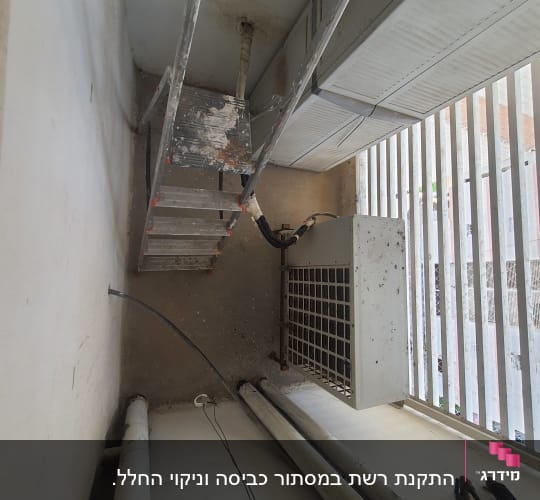 סולם מתכת ליד מזגן חיצוני עם צינורות חשופים
